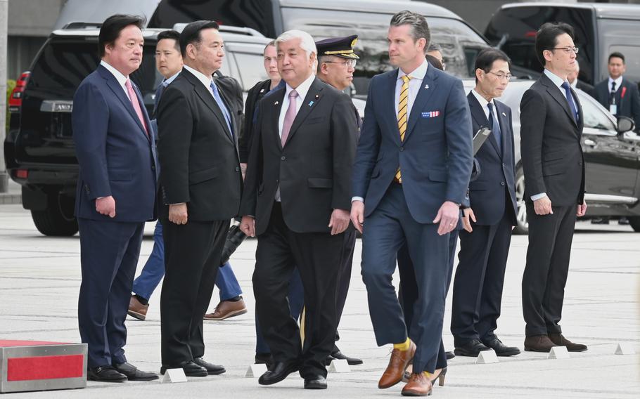 Pete Hegseth and the Japanese minister of defense walk past Japanese officials. 