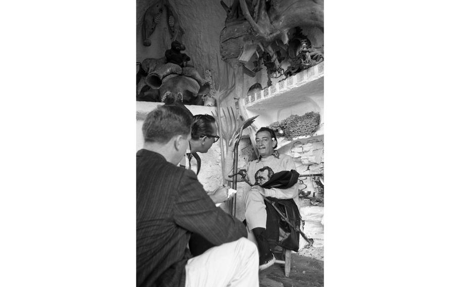 Salvador Dali being interviewed by Stars and Stripes reporter Wallace Beene (glasses) in the library of the surrealist's home and studio in Port Lligat, on the Spanish Costa Brava.