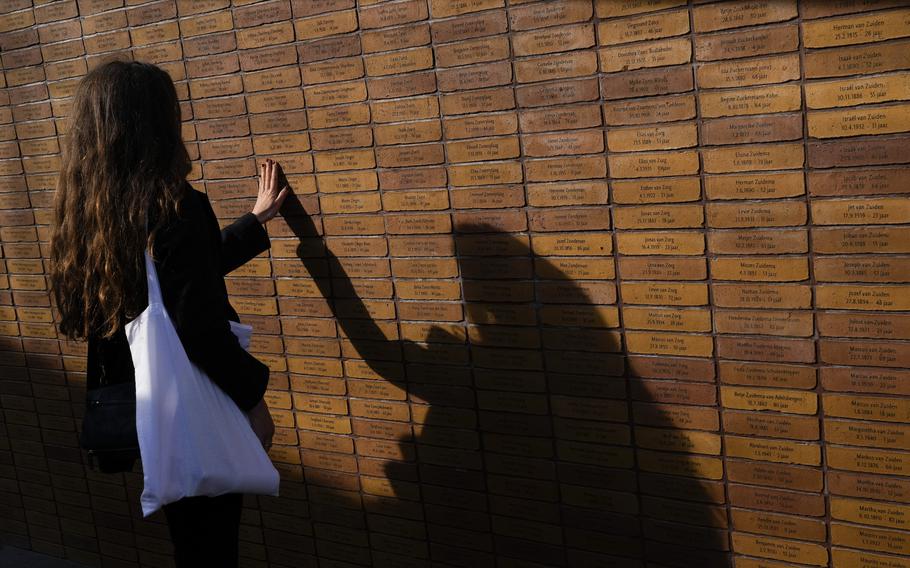 A woman touches one of the name stones after King Willem-Alexander officially unveiled a new monument in the heart of Amsterdam’s historic Jewish Quarter on Sunday, Sept. 19, 2021, honoring the 102,000 Dutch victims of the Holocaust. 