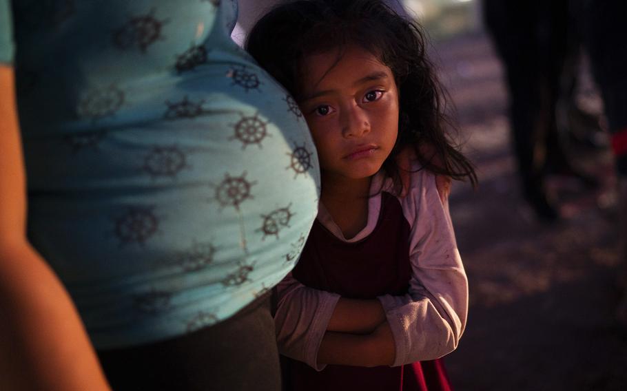 A young Guatemalan girl leans on her mother’s pregnant stomach in Eagle Pass.