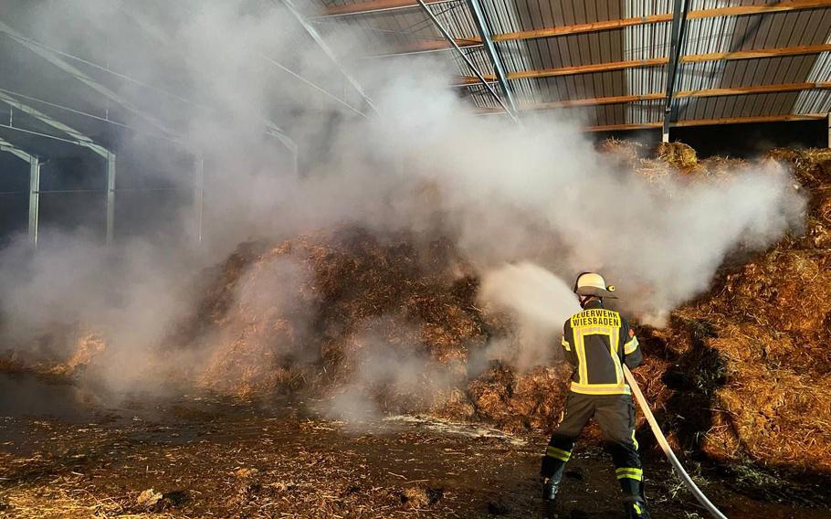 A firefighter extinguishes flames at an agricultural storage area in Delkenheim, Germany, early Tuesday, Dec. 28, 2021. U.S. Army firefighters stationed at Wiesbaden helped their German counterparts. 