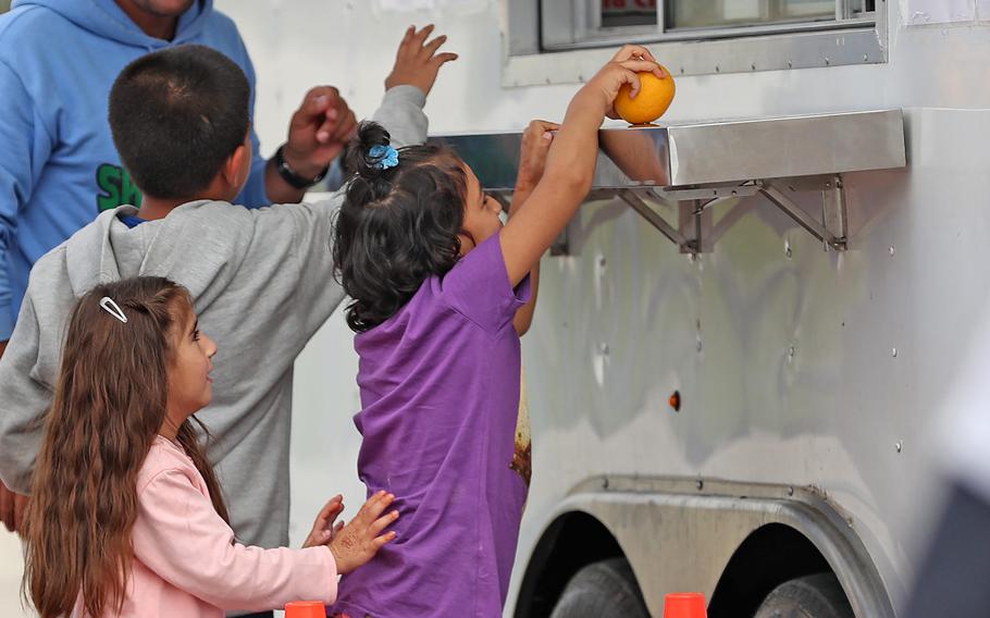 Children get fruit at a grab and go truck outside a community at the Operation Allies Welcome Afghan evacuees settlement Oct. 14, 2021, at Camp Atterbury in Edinburgh, Ind.