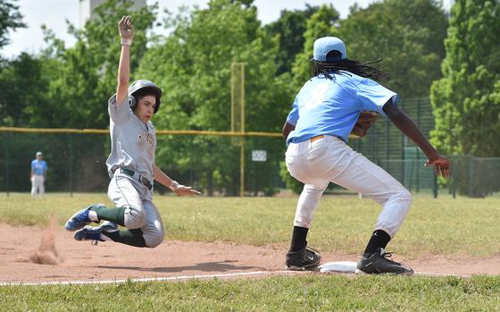 Naples freshman Davis Mauns slides into third base during the Divisions II/III DODEA European baseball championship game against Sigonella on May 20, 2023, at Southside Fitness Center on Ramstein Air Base, Germany. Applying the tag is Jaguar third baseman DeShawn Wallace.