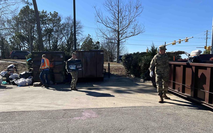Army Col. John Wilcox, the Fort Liberty garrison commander, Command Sgt. Maj. Gregory Seymour, and installation public works employees move trash to alleviate the garbage overflow at the North Carolina installation. 