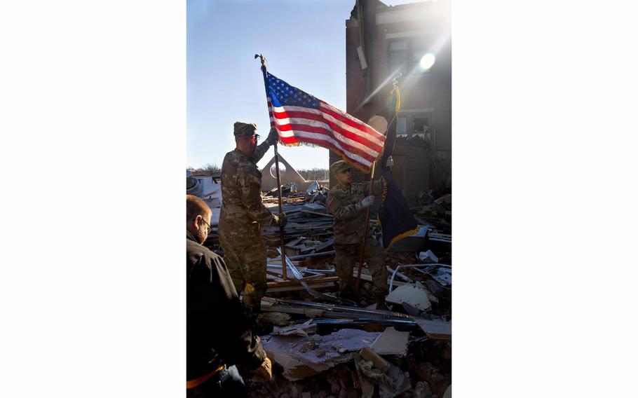 Spc. James Smithson, 22, a truck driver with the Kentucky National Guard, helps remove the state’s flag from among the debris of the Graves County Courthouse in his hometown of Mayfield, Ky. The town was one of the worst damaged Friday when a several tornadoes touched down in the state.