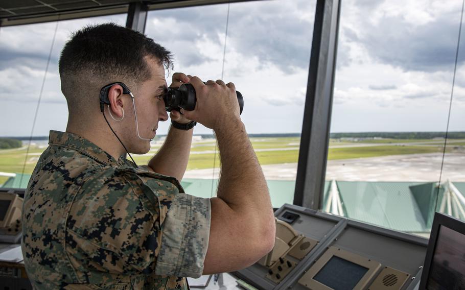 Marine Corps Cpl. Matheus Stitt looks through binoculars at a control tower at Marine Corps Air Station New River, N.C., on May 13, 2021. 