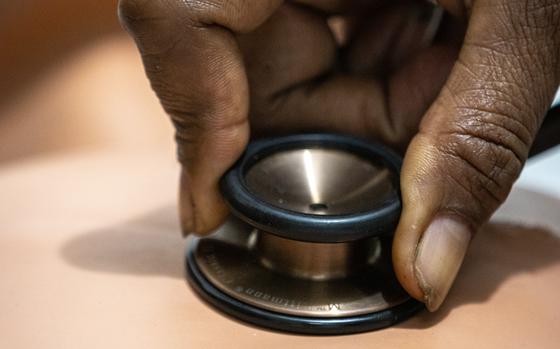 A stethoscope is held to a training dummy’s chest.