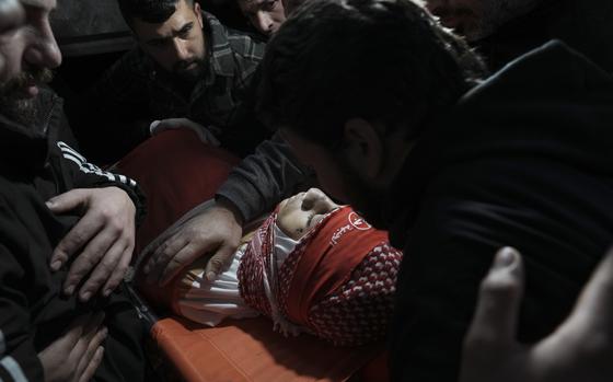 Mourners gather around the body of 14-year-old Palestinian Omar Khumour during his funeral in the West Bank city of Bethlehem, Monday, Jan. 16, 2023. The Palestinian Health Ministry said Khumour died after being struck in the head by a bullet during an Israeli military raid into Dheisha refugee camp near the city of Bethlehem. The Israeli army said that forces entered the Dheisha camp and were bombarded by Molotov cocktails and rocks. It said soldiers responded to the onslaught with live fire. (AP Photo/Mahmoud Illean)