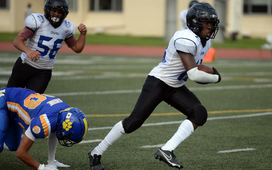 Osan's Aaron Patterson breaks free from Yokota's Theo Shone after intercepting a pass.