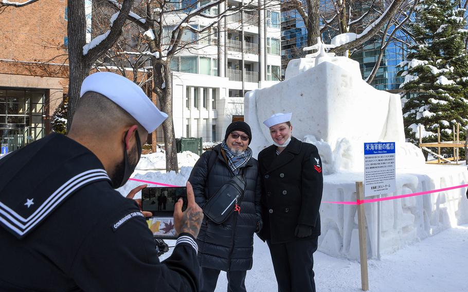 A sailor poses with a Japanese man in front of the Navy's ice sculpture at the Sapporo Snow Festival in Hokkaido, Japan, Feb. 4, 2023. 