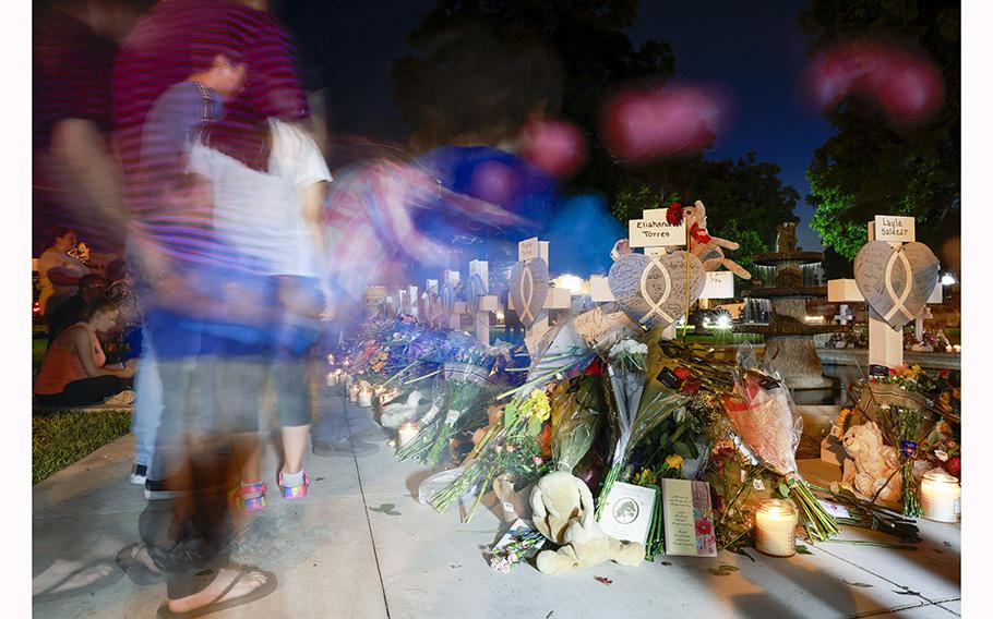 A long exposure photograph shows people around a memorial for victims of the Robb Elementary School shooting at the town square in Uvalde on May 26, 2022. 