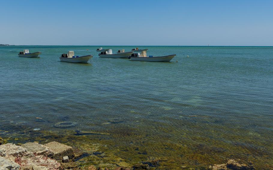 Fishing boats anchored off a beach.