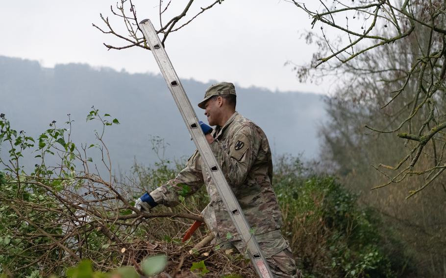 Master Sgt. Kirk Thompson works to remove thick vegetation that grew into a historic stone wall in St. Goar, Germany, on Feb. 23, 2023.