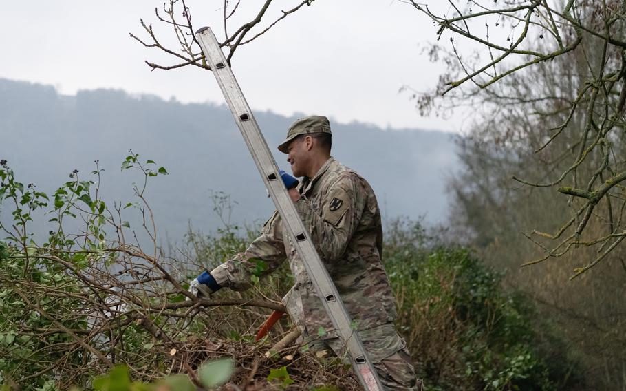 Master Sgt. Kirk Thompson works to remove thick vegetation that grew into a historic stone wall in St. Goar, Germany, on Feb. 23, 2023.