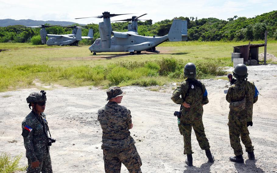 Service members from the Philippines, U.S. and Japan watch a Marine Corps MV-22B Osprey land.