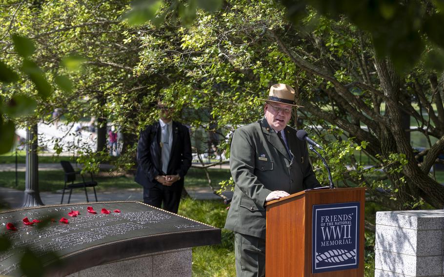 A man in a suit and wide brimmed hat speaks at a podium.