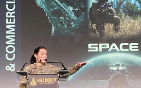 Space Force Brig. Gen. Kristin Panzenhagen gestures with one hand as she gives a speech at a podium.