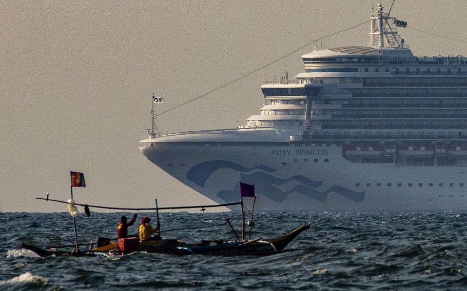 A small fishing boat passes by the cruise ship, Ruby Princess on May 7, 2020, in the waters of Manila Bay, Philippines. 