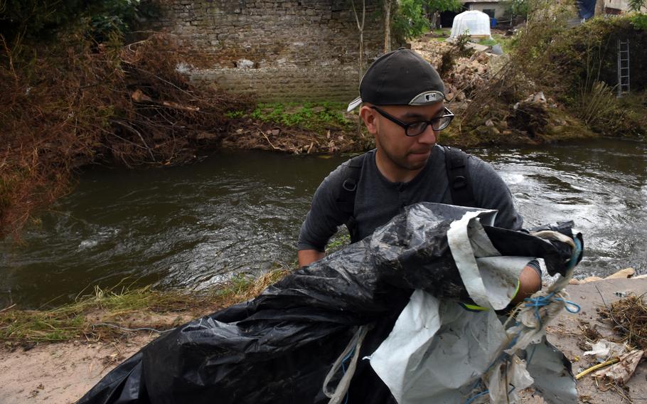 Senior Airman Calixto Rodriguez of Spangdahlem Air Base, Germany, removes trash from the banks of the Nims River in Rittersdorf on July 31, 2021. More than two dozen airmen from the base volunteered to help clean up the river in the aftermath of last month’s severe flooding in western Germany.