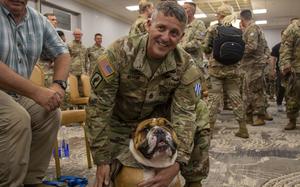 A soldier embraces Rocky the Bulldog, the live mascot for the division.