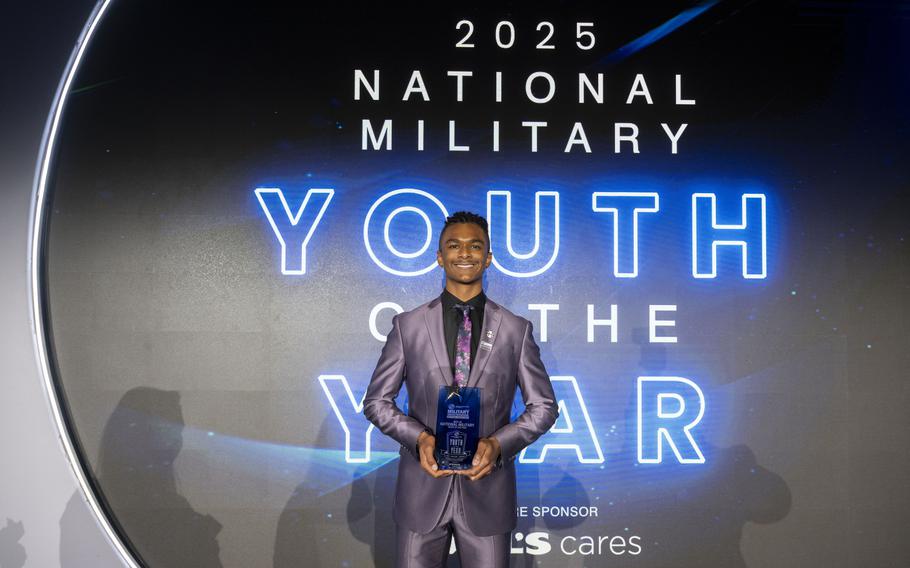 A teenager smiles and holds an award.