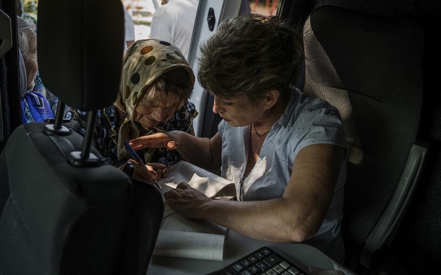 Postal worker Alona Osukhovska helps a woman sign for her pension check. 