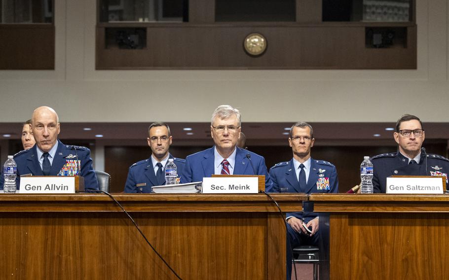 Allvin in uniform, Meink and Saltzman, also in uniform, at a table in the hearing room with nameplates in front of them.
