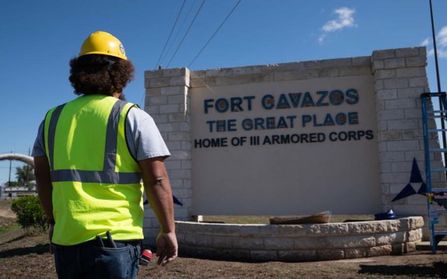 A government contractor examines a new gate sign at Fort Cavazos, Texas. 