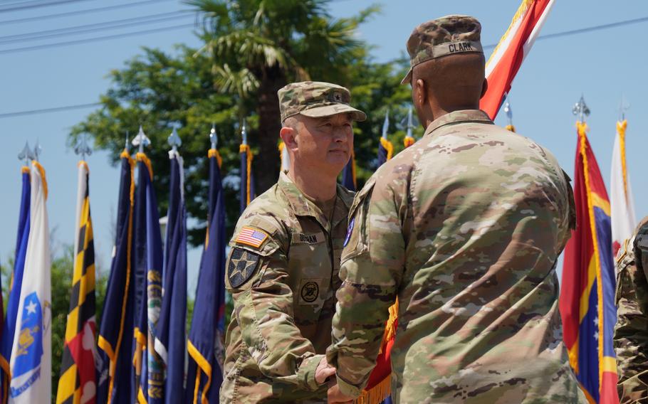 Brig. Gen. James Dooghan reaches for the U.S. Army Japan guidon as Gen. Ronald Clark hands it over during an outdoor ceremony.