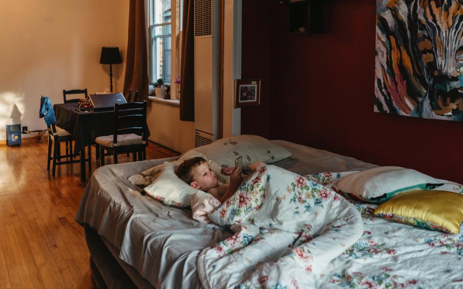 Ilya Dmytro, 4, lays in bed and watches cartoons on a phone in his family's apartment. 
