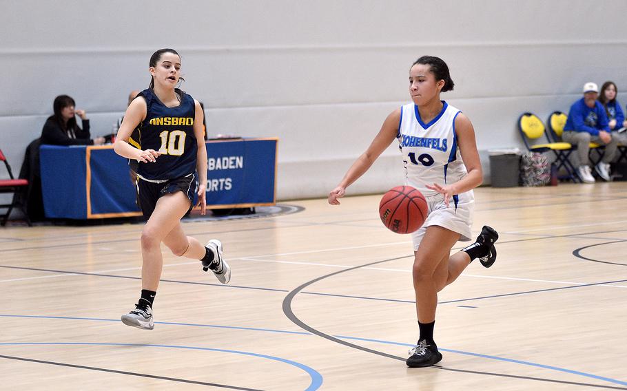 Hohenfels junior Malea Jobity dribbles on the fast break as Ansbach junior Abecca Ackles trails the play during pool-play action of the DODEA European basketball championships on Feb. 14, 2024, at the Wiesbaden Sports and Fitness Center on Clay Kaserne in Wiesbaden, Germany.