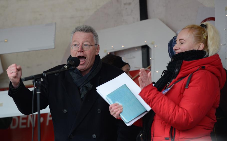 German right-wing politician Markus Beisicht demands American troops leave Germany as event organizer Elena Kolbasnikova applauds on stage above a large pro-Russia peace protest in downtown Ramstein-Miesebach, Germany, on Feb. 26, 2023.