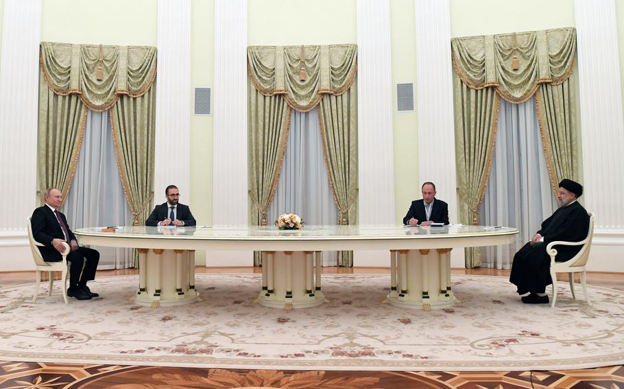 Russian President Vladimir Putin, left, and Iranian President Ebrahim Raisi, right, talk to each other during their meeting in the Kremlin in Moscow, Russia, Wednesday, Jan. 19, 2022.