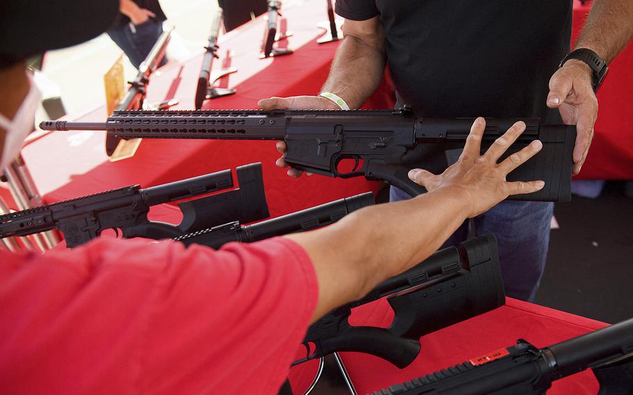A clerk shows a customer a TPM Arms LLC California-legal featureless AR-10 style .308 rifle displayed for sale at the company’s booth at the Crossroads of the West Gun Show at the Orange County Fairgrounds on June 5, 2021, in Costa Mesa, California. 