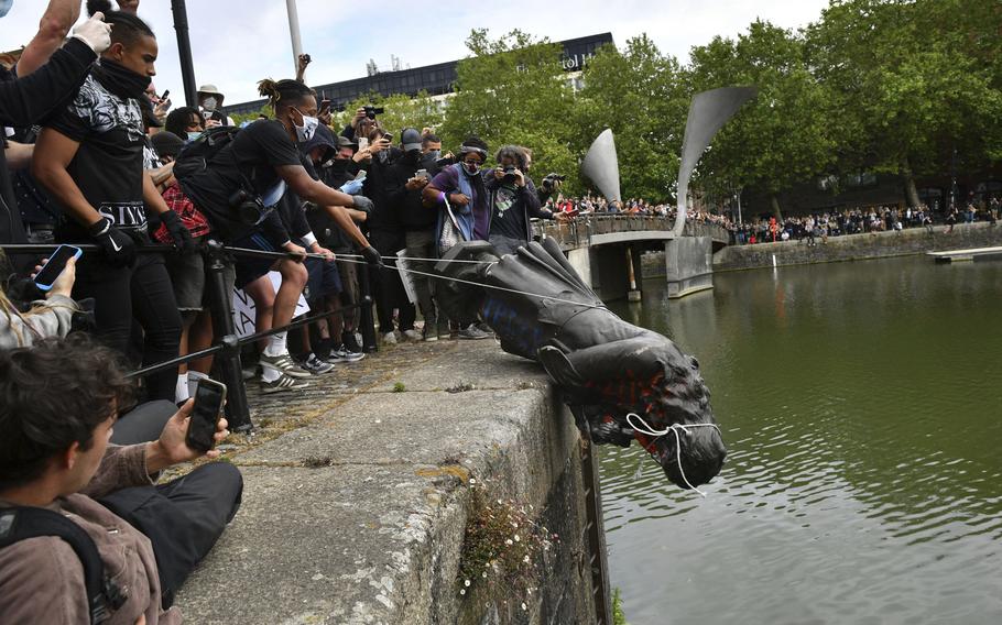 Protesters throw a statue of Edward Colston into the Bristol harbour during a Black Lives Matter protest rally, in Bristol, England, on June 7, 2020. 