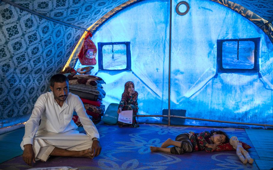 Abdullah Eid Mohamed, 33, with two of his girls at the Jeddah camp. Maria, 3, sleeps beside a doll without arms. 