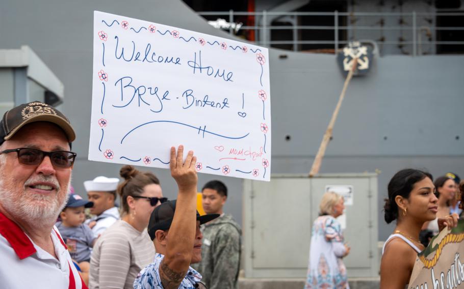 A family holds up a sign saying Welcome Home.