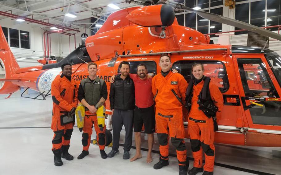 In this photo provided by the U.S. Coast Guard, kayaker Cyril Derreumaux, in shorts, poses with the Coast Guard helicopter crew that rescued him off the California coast in San Francisco on Saturday, June 5, 2021.
