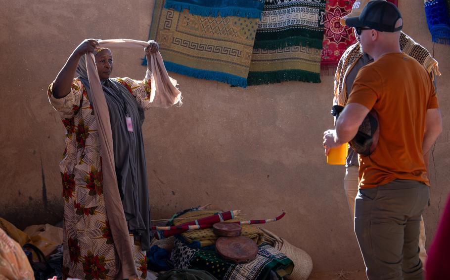 A women's bazaar vendor demonstrates how to wear traditional African clothing to U.S. service members at Base 201 in Agadez, Niger, on Dec. 2, 2023. The bazaar brought together American troops and Nigeriens from the Agadez area.