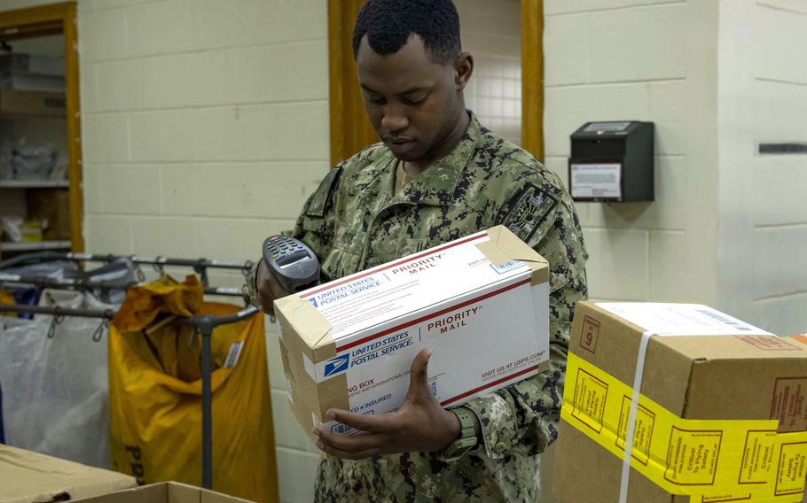 Petty Officer 3rd Class Richard Reddick scans and sorts mail at the Navy post office at Kadena Air Base, Japan, on Dec. 2, 2021. 