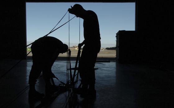Yokota Air Base, Japan, Oct. 25, 2006: Staff Sgt Jeremy Hayes and Staff Sgt. John Paszkot unfurl a G-12E 64-foot parachute used for heavy equipment delivery. They were taking the Fabrication of Aerial Delivery Loads Course at Yokota Air Base, Japan. The course runs for two weeks and certifies all who complete it to inspect the chutes.