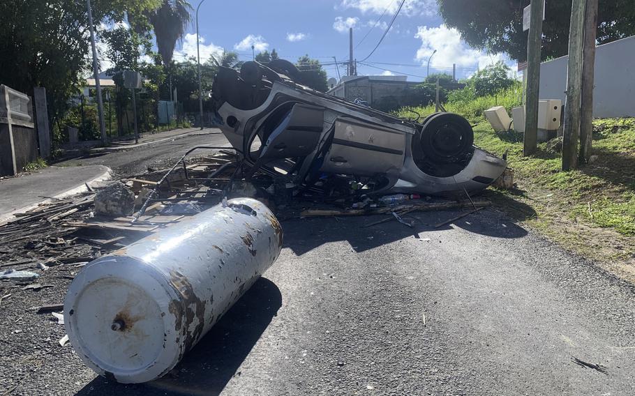 An overturned car is pictured in a s street of Le Gosier, Guadeloupe island, Sunday, Nov. 21, 2021. French authorities are sending police special forces to the Caribbean island of Guadeloupe, an overseas territory of France, as protests over COVID-19 restrictions erupted into rioting.