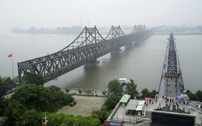 Visitors walk across the Yalu River Broken Bridge, right, next to the Friendship Bridge connecting China and North Korea in Dandong in northeastern China's Liaoning province, Sept. 9, 2017. North Korea and China resumed freight train service Monday, Sept. 26, 2022, following a five-month hiatus, South Korean officials said, as the North struggles to revive an economy battered by the pandemic, U.N. sanctions and other factors. 