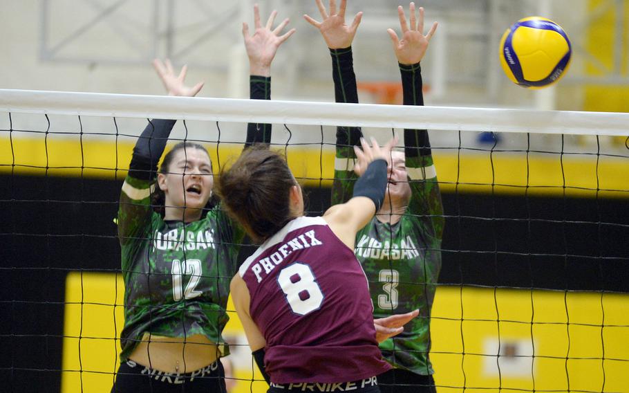 Seisen's Lisa Purcell spikes against Kubasaki's Olivia Schaffeld and Adria Lockhart.