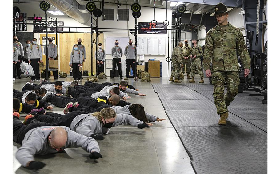 Alaska Army National Guard’s newest soldiers are put in the “prone row” position as  drill sergeant Sgt. 1st Class Jason Schlegel walks past  at Camp Carrol on Joint Base Elmendorf-Richardson, on Oct. 25, 2020, during a drill weekend with the Recruit and Sustainment Program.