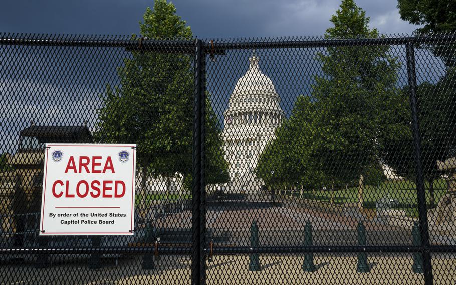 The U.S. Capitol is seen under dark skies in Washington, Tuesday, June 8, 2021, as barriers remain six months after the Jan. 6 attack.