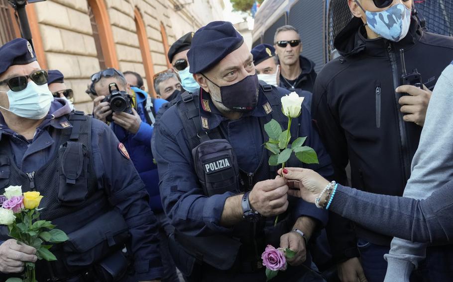 Demonstrators bring flowers to police officers, Friday, Oct. 15, 2021, at Rome’s Circus Maximus during a protest against a new anti COVID-19 measure requiring all workers to show a health pass to enter their place of employment. 