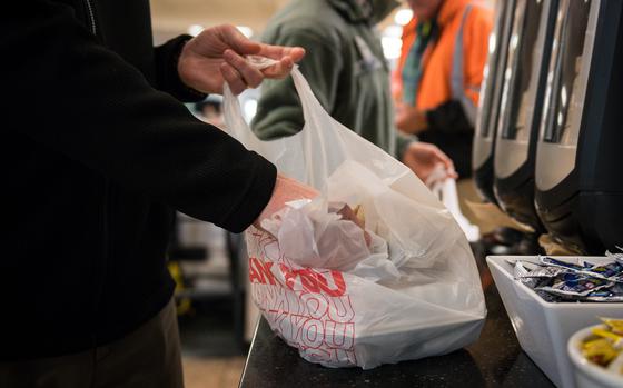 A takeout meal is placed into a plastic bag.