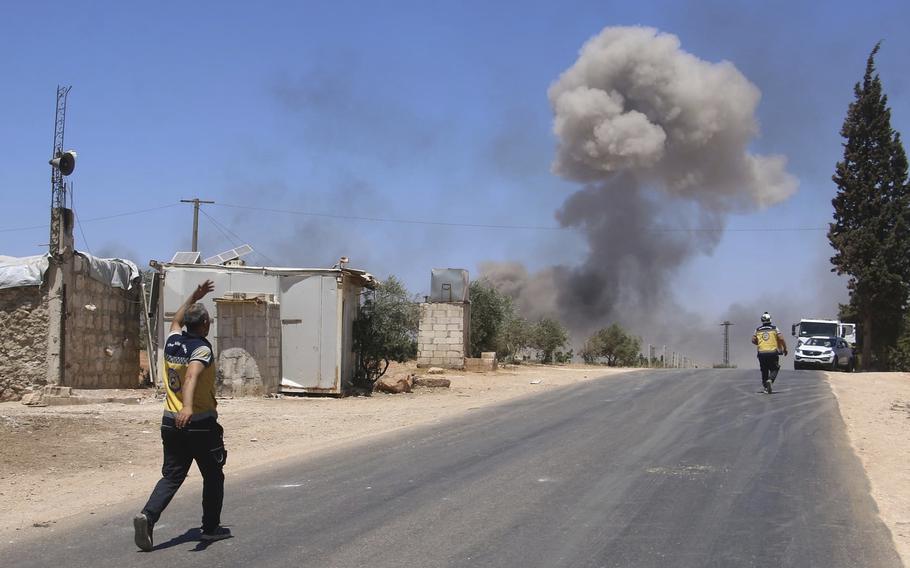 Syrian Civil Defense workers run at the explosion scene in Maarat Misrin village