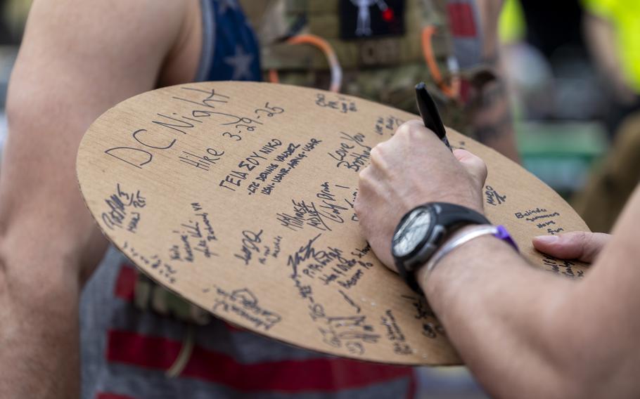 A person signs a circle of cardboard with a marker